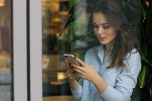 kobieta czyta wiadomosc ze smartfona 300x200 Jaką usługę VoIP dla komórki warto wybrać?